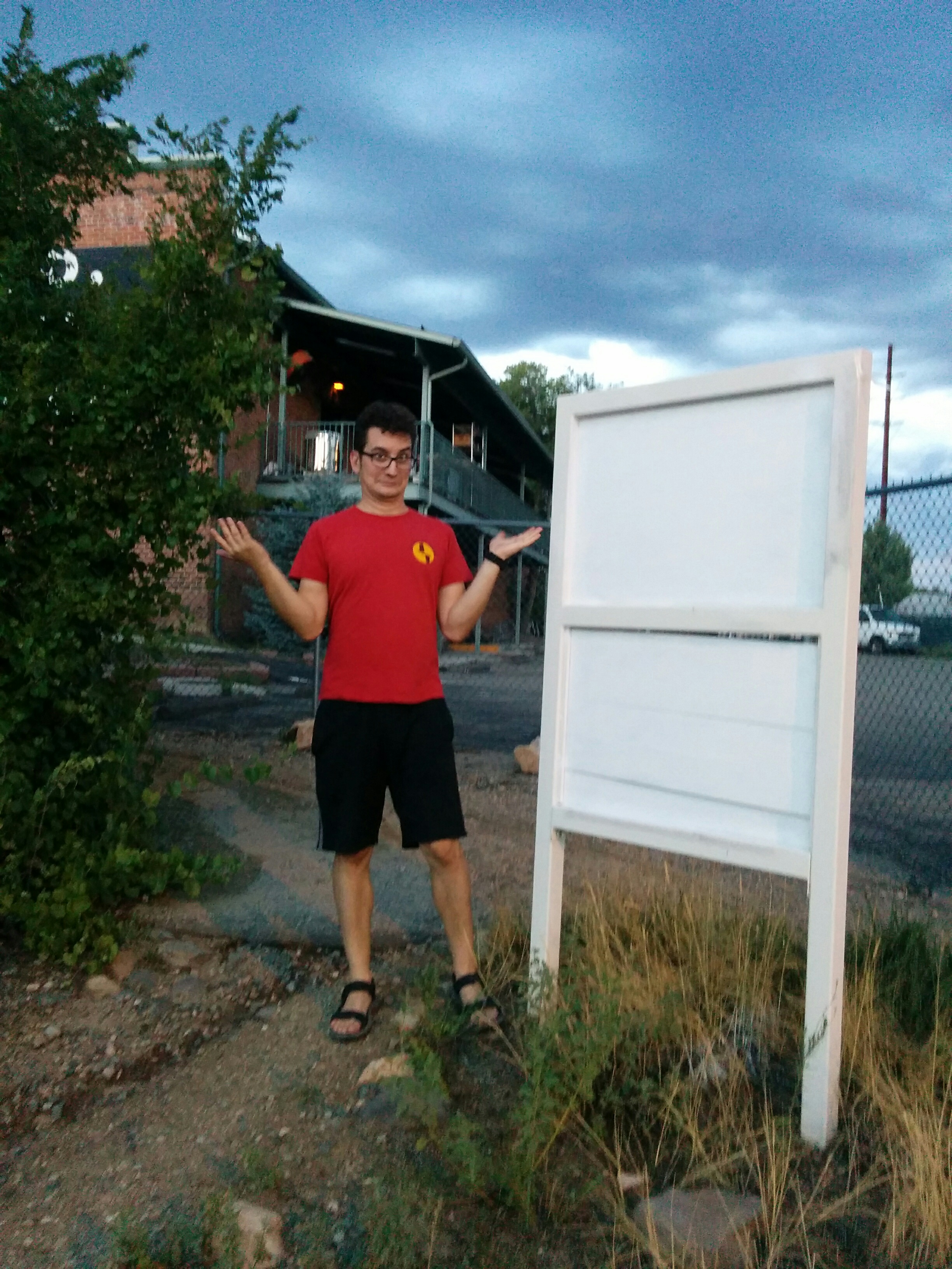 Me shrugging in confusion in front of a useless, blank sign.